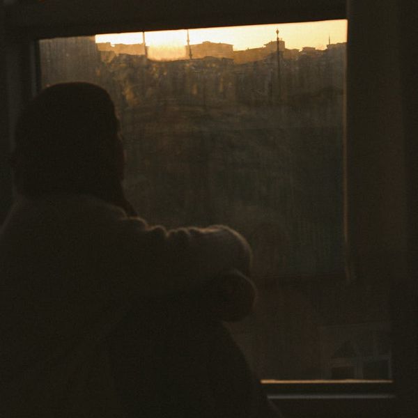 Person meditating peacefully by a window with soft light coming through.